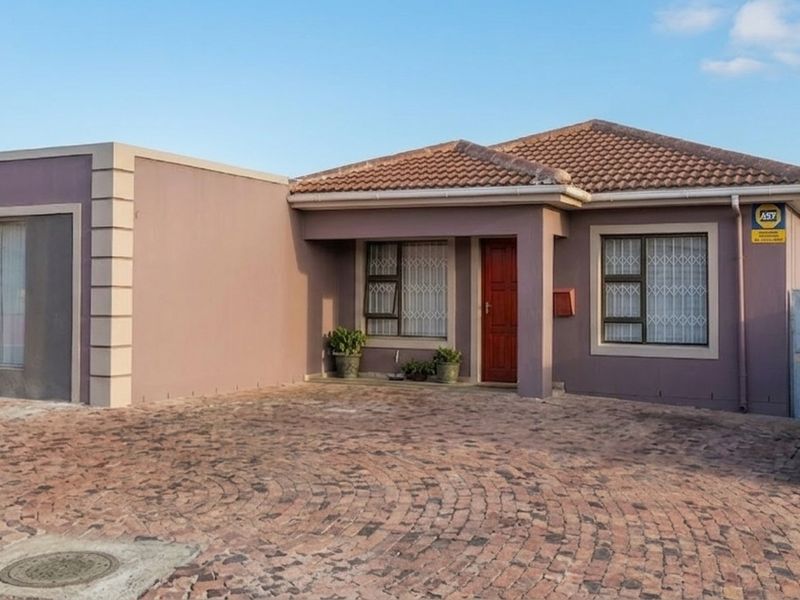 Front elevation of a single-story house featuring a paved driveway, tiled roof, and secure entrance with burglar bars.