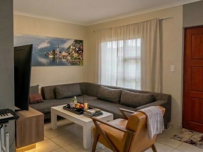 A comfortable living room featuring tiled flooring and a solid timber entrance door, providing a functional and inviting space.