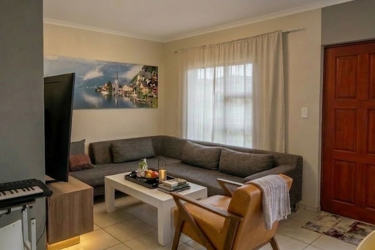 A comfortable living room featuring tiled flooring and a solid timber entrance door, providing a functional and inviting space.