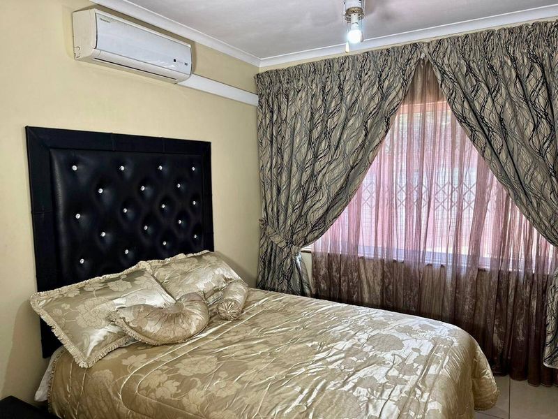 A bedroom featuring a wall-mounted split-system air conditioner, cove cornicing, and security bars on the window.