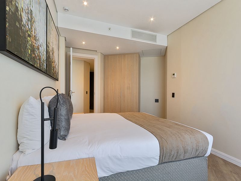A well-maintained bedroom featuring built-in wardrobes, recessed downlighting, and integrated ducted air conditioning, finished with modern timber-look flooring.