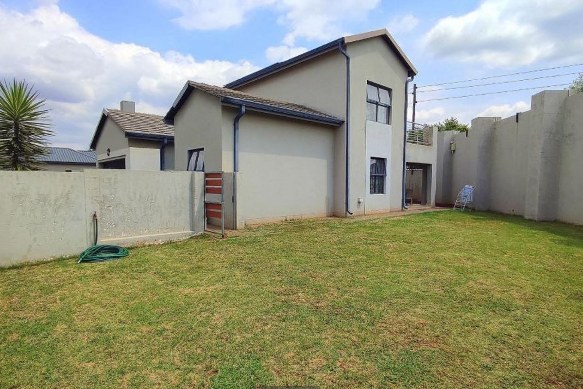 Rear view of the double-storey house featuring a private garden, perimeter walling, and tiled roof structure.
