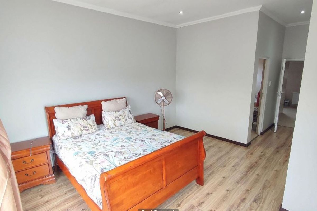 A well-maintained bedroom featuring light-toned laminate flooring, neutral wall finishes, and recessed downlighting, providing a clean and functional living space.