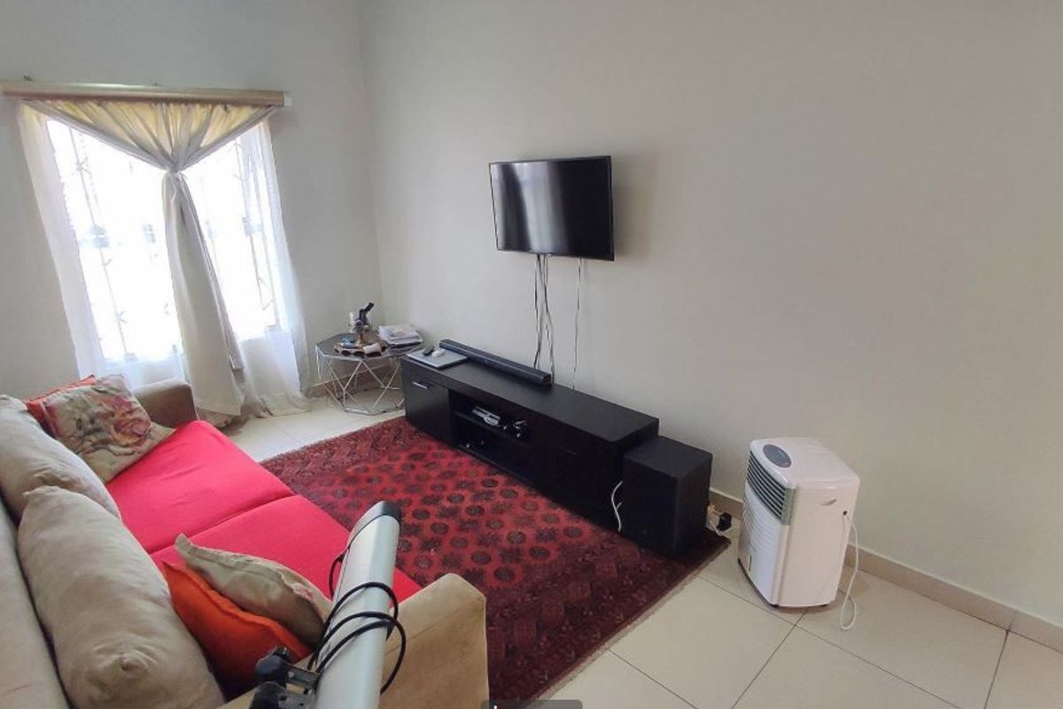 A functional living room featuring tiled flooring and a window with a curtain rod, providing a neutral base for interior design.