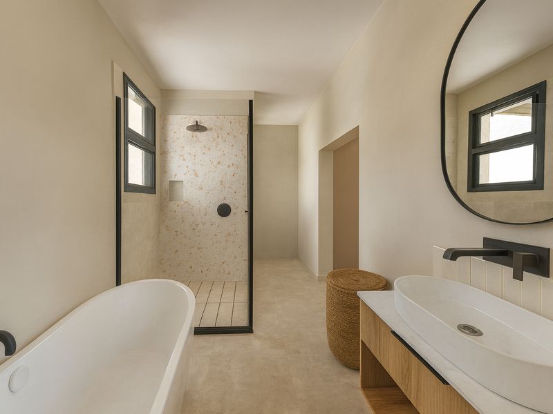 Modern bathroom featuring a freestanding bathtub, walk-in shower with terrazzo tiling, vanity with vessel sink, and matte black fixtures.