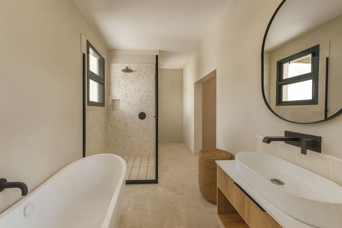 Modern bathroom featuring a freestanding bathtub, walk-in shower with terrazzo tiling, vanity with vessel sink, and matte black fixtures.