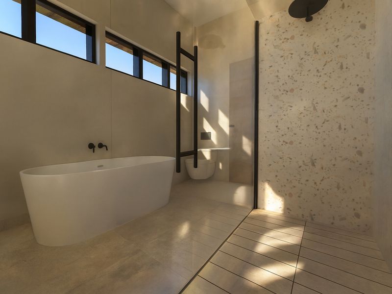Modern luxury bathroom featuring a freestanding bathtub, walk-in shower with terrazzo tiling, black matte fixtures, and high-level clerestory windows for natural light.