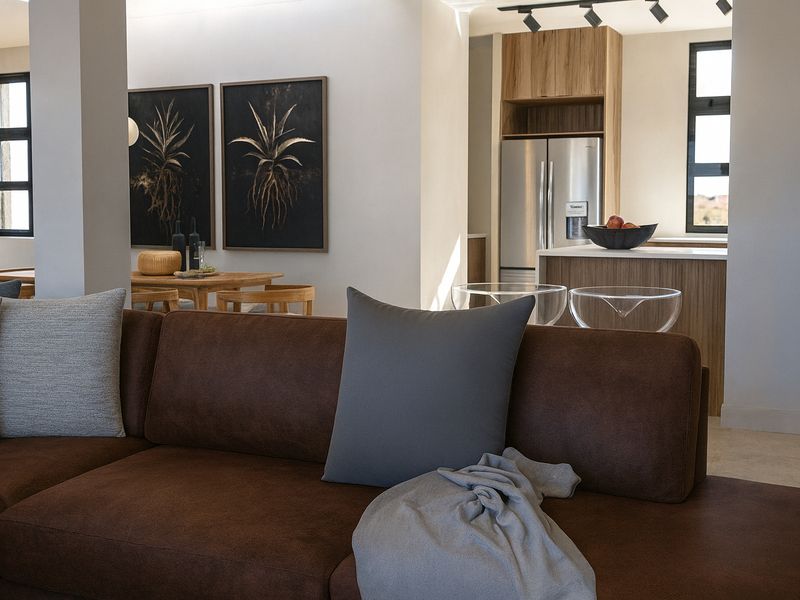 Modern open-plan living area featuring a contemporary kitchen with island, sleek cabinetry, and track lighting, seamlessly flowing into the dining and lounge space.