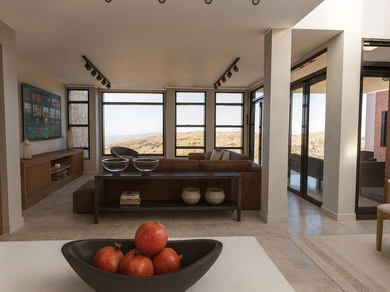 Modern open-plan living area featuring large windows with scenic views, track lighting, and neutral tiled flooring, seamlessly connecting to outdoor spaces.