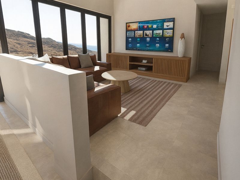 Modern living room featuring a vaulted ceiling, large format floor tiles, and expansive black-framed windows offering scenic views.