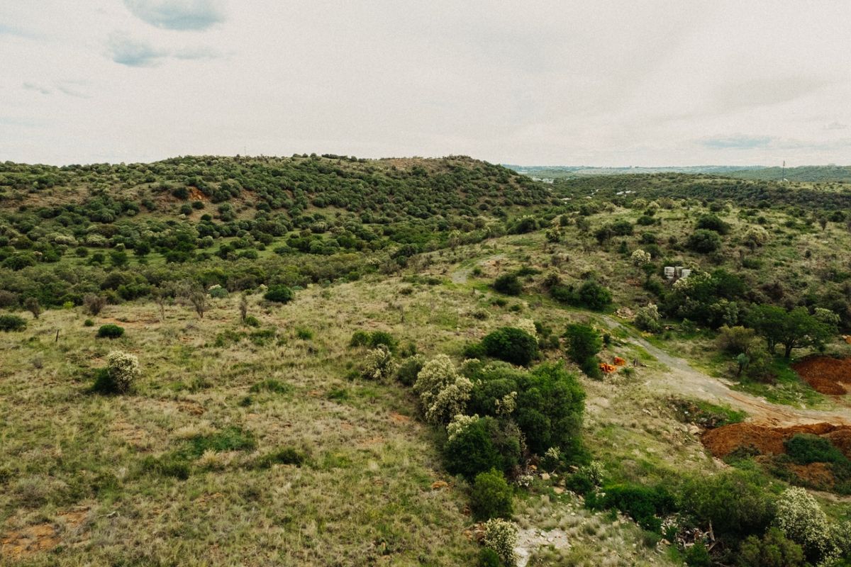 An aerial view of a large, undeveloped residential plot featuring natural landscape, native vegetation, and rolling terrain.