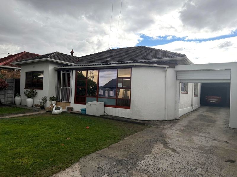 Front view of a single-story house featuring a tiled roof, concrete driveway, and an attached carport.