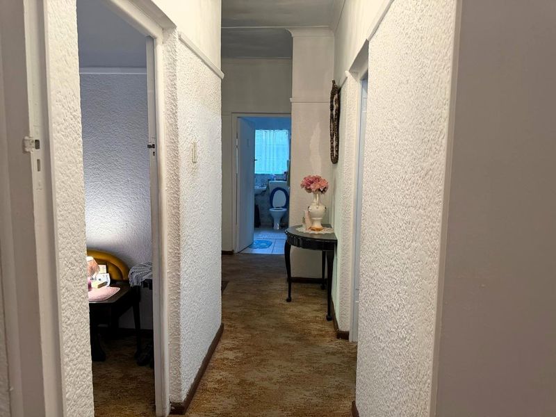 A residential hallway featuring textured wall finishes and carpet flooring, providing access to adjacent rooms including a bathroom.