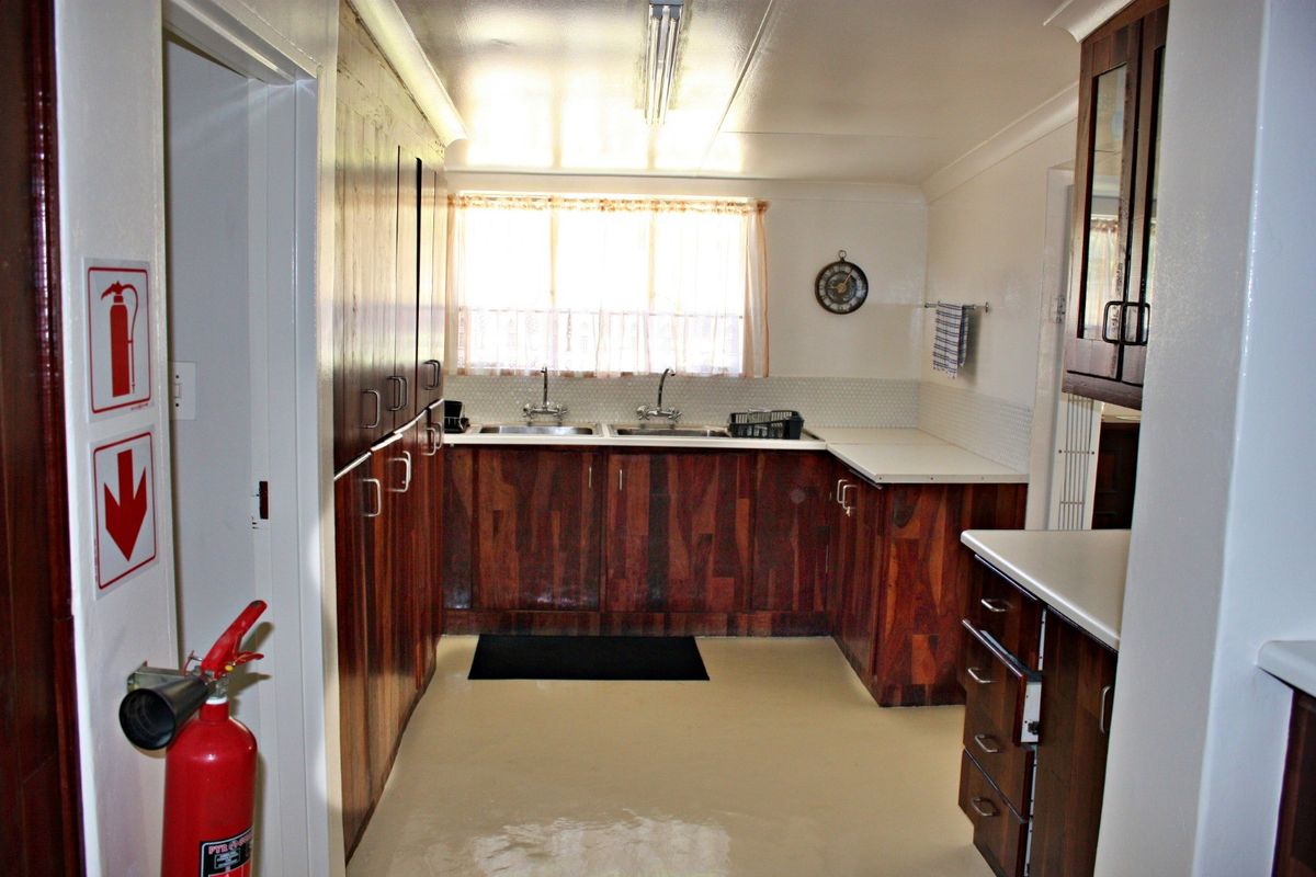 A functional kitchen featuring dark wood cabinetry, dual stainless steel sinks, and ample storage space with a neutral floor finish.