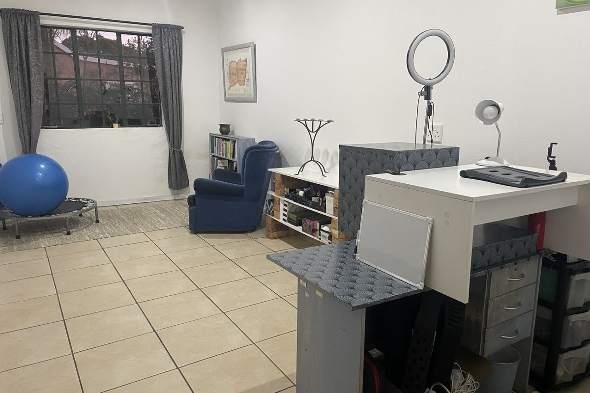 A multi-purpose living area featuring neutral tiled flooring and a large metal-framed window, offering a versatile space for various uses.
