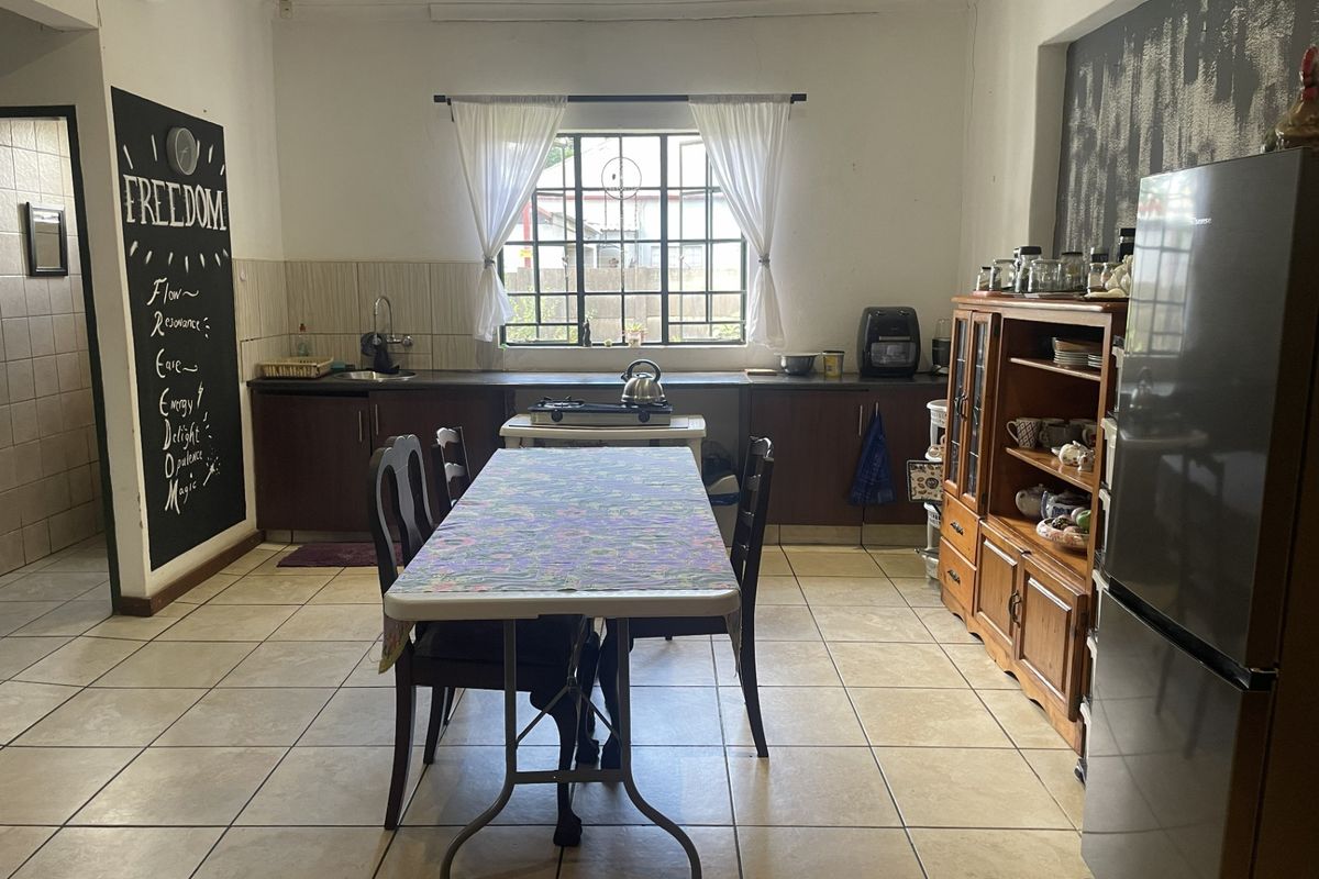 A functional kitchen featuring tiled flooring, built-in cabinetry, and a window with security bars, offering a practical layout for daily use.