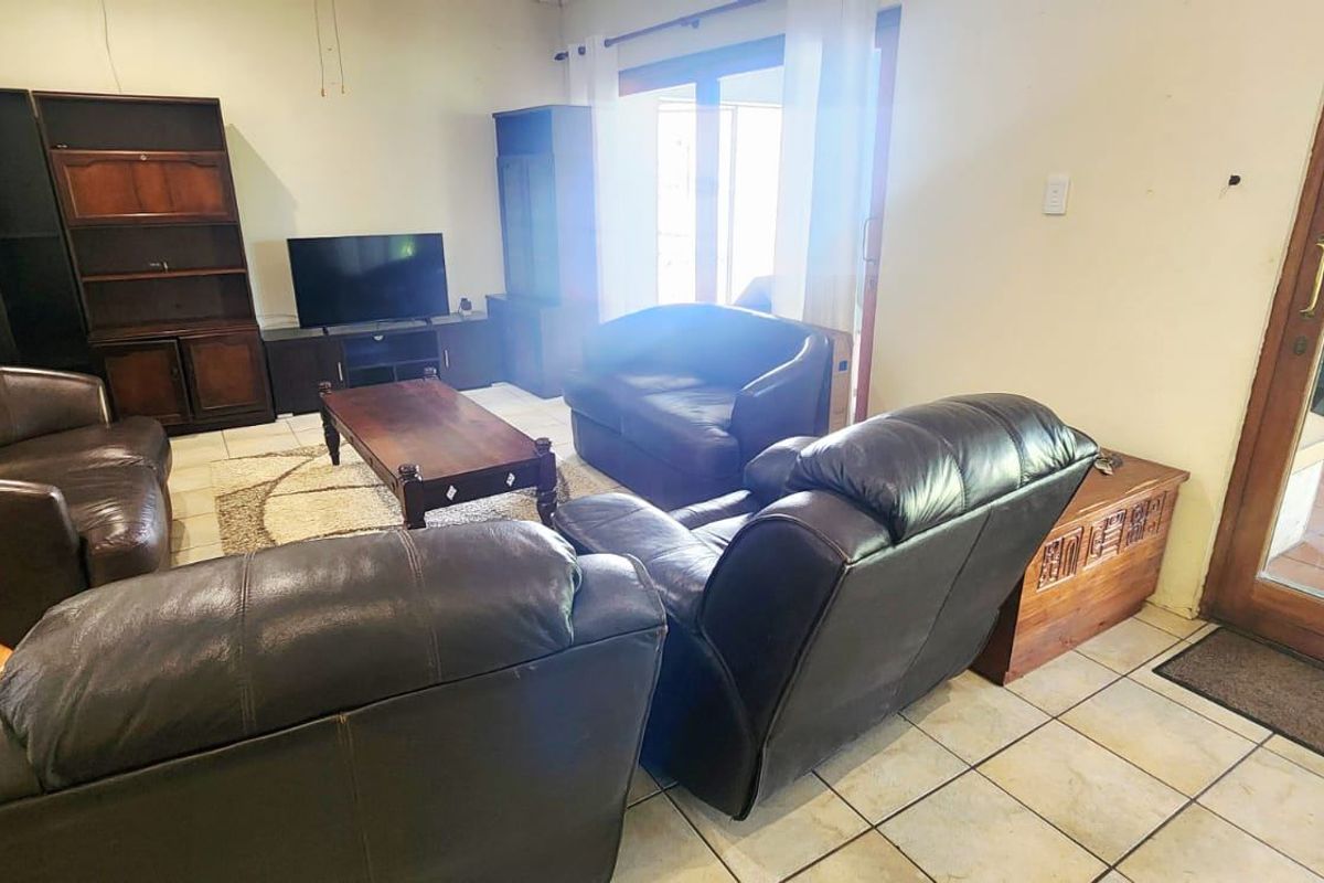 A living room featuring tiled flooring and a sliding glass door providing access to an outdoor area.