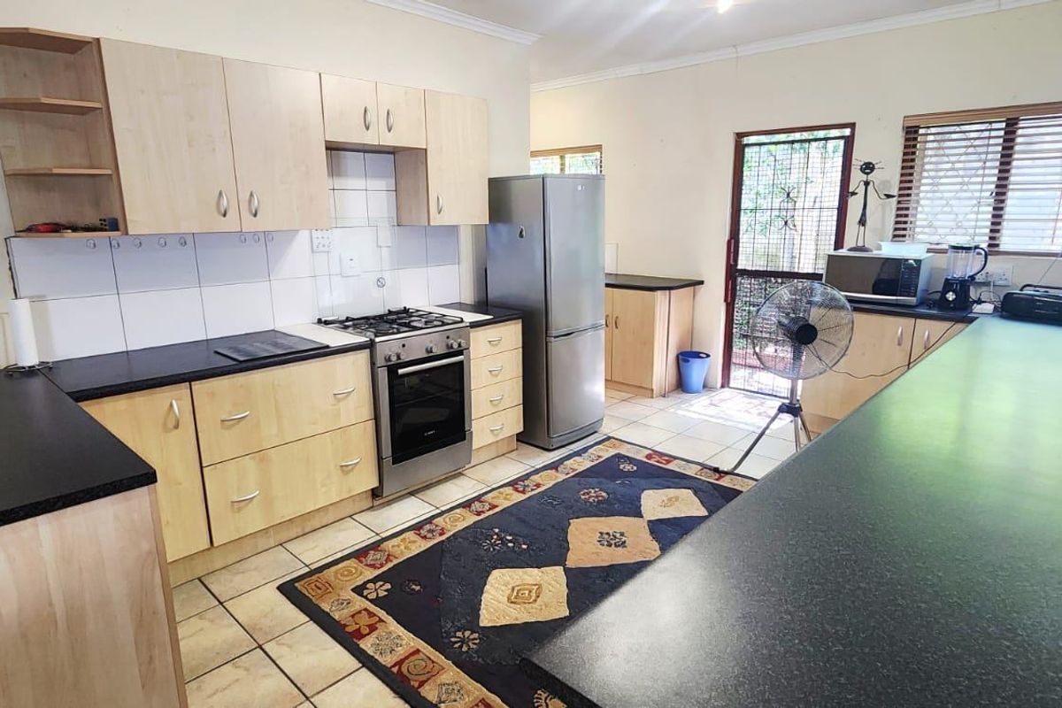 Functional kitchen featuring light wood-tone cabinetry, dark laminate countertops, gas stove, and a breakfast bar area with tiled flooring.