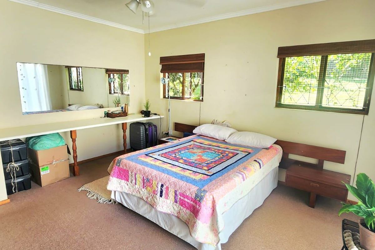 Spacious bedroom featuring a built-in vanity with mirror, integrated headboard, ceiling fan, and carpeted flooring.
