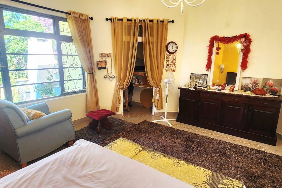 A spacious bedroom featuring large windows that provide ample natural light, tiled flooring, and a built-in closet area.