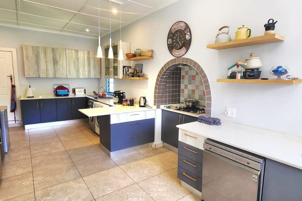 A functional kitchen featuring modern two-tone cabinetry, stone countertops, an integrated stove alcove with decorative tiling, and tiled flooring throughout.