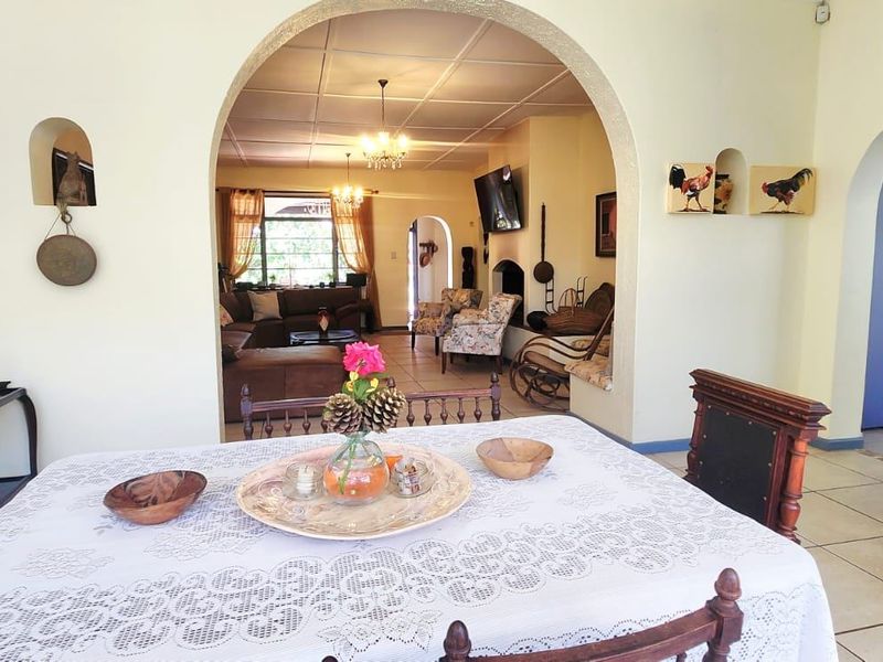 Open-plan living and dining area featuring classic arched doorways, tiled flooring, and a built-in fireplace, creating a warm and connected living space.