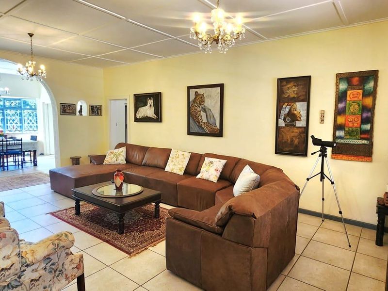 Spacious open-plan living and dining area featuring tiled floors, an arched transition between spaces, and classic chandelier lighting.