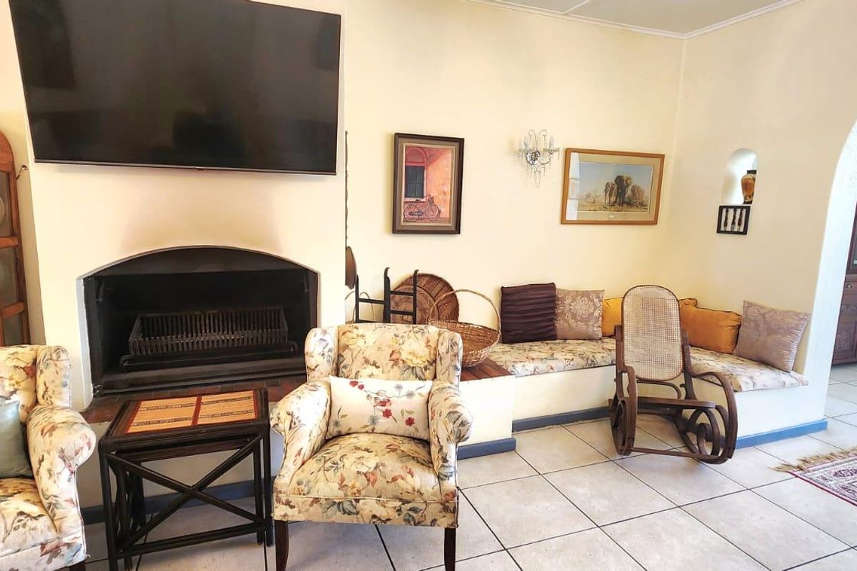 A cozy living room featuring a built-in fireplace, integrated bench seating, and tiled flooring, connected to adjacent spaces via a classic archway.