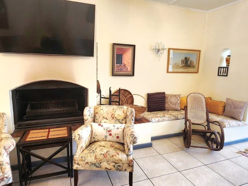 A cozy living room featuring a built-in fireplace, integrated bench seating, and tiled flooring, connected to adjacent spaces via a classic archway.