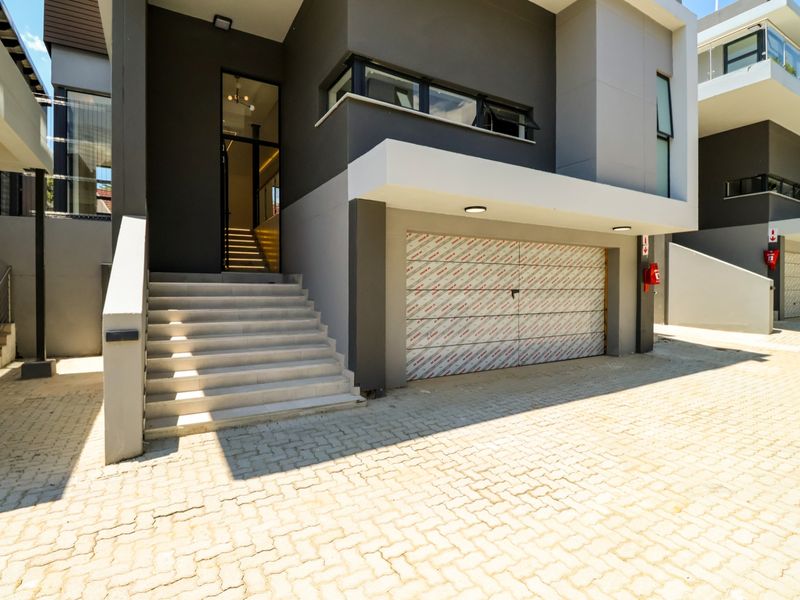 Modern double-storey cluster home featuring a paved driveway, integrated double garage with protective film, and a welcoming staircase leading to the main entrance.