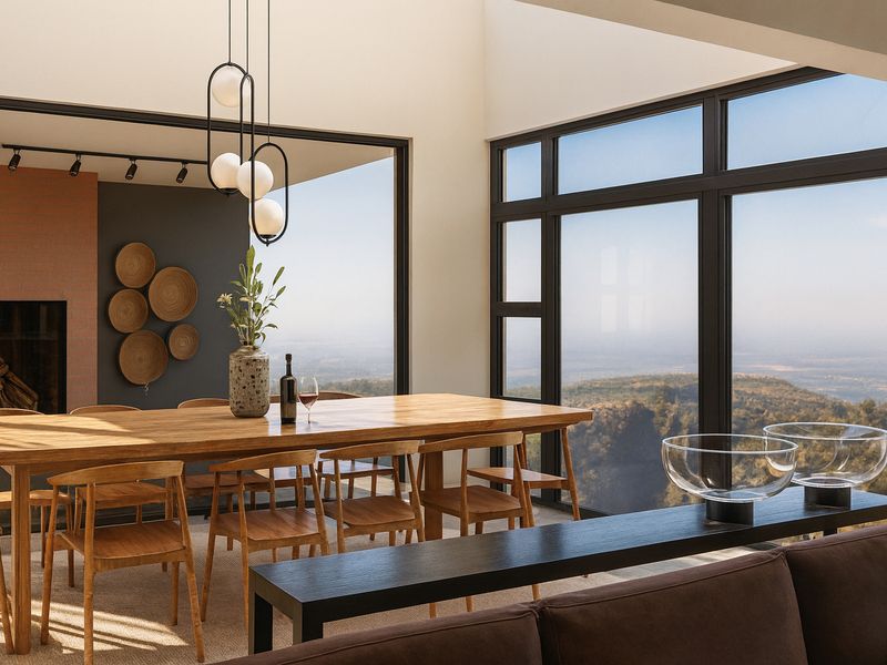 Spacious open-plan dining area featuring a built-in fireplace, vaulted ceilings, and expansive windows offering panoramic landscape views.