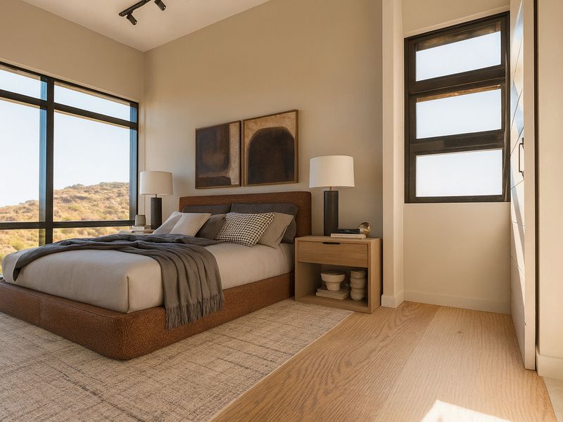 Modern bedroom featuring expansive windows with scenic views, high-quality hardwood flooring, and contemporary track lighting in a well-maintained, bright space.