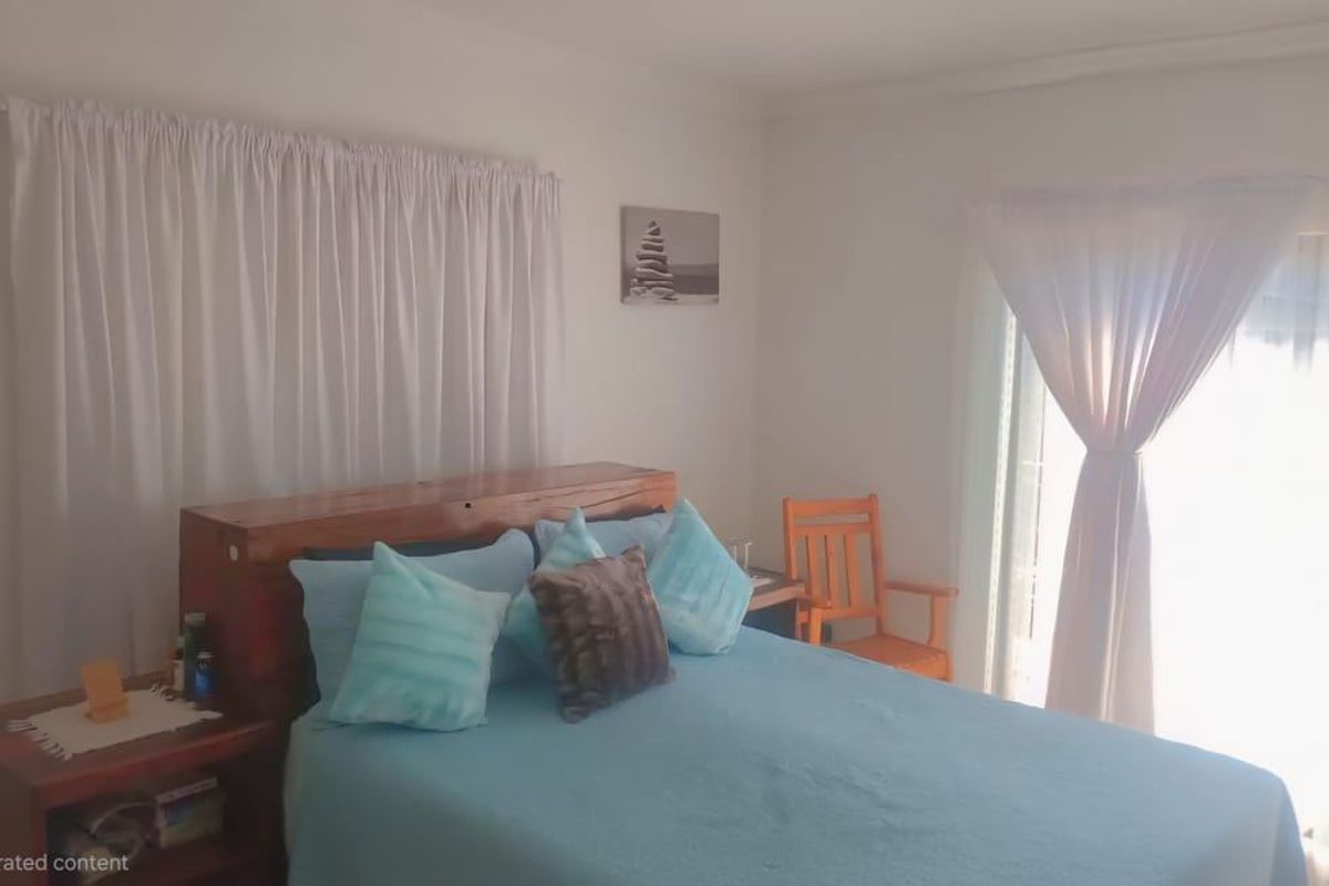 A bedroom featuring a large window with curtains, providing natural light and access to the exterior.