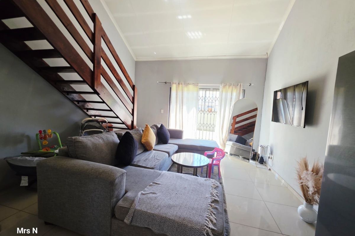 Open-plan living area featuring tiled flooring, a wooden staircase with balustrade, and a sliding door leading to the exterior.