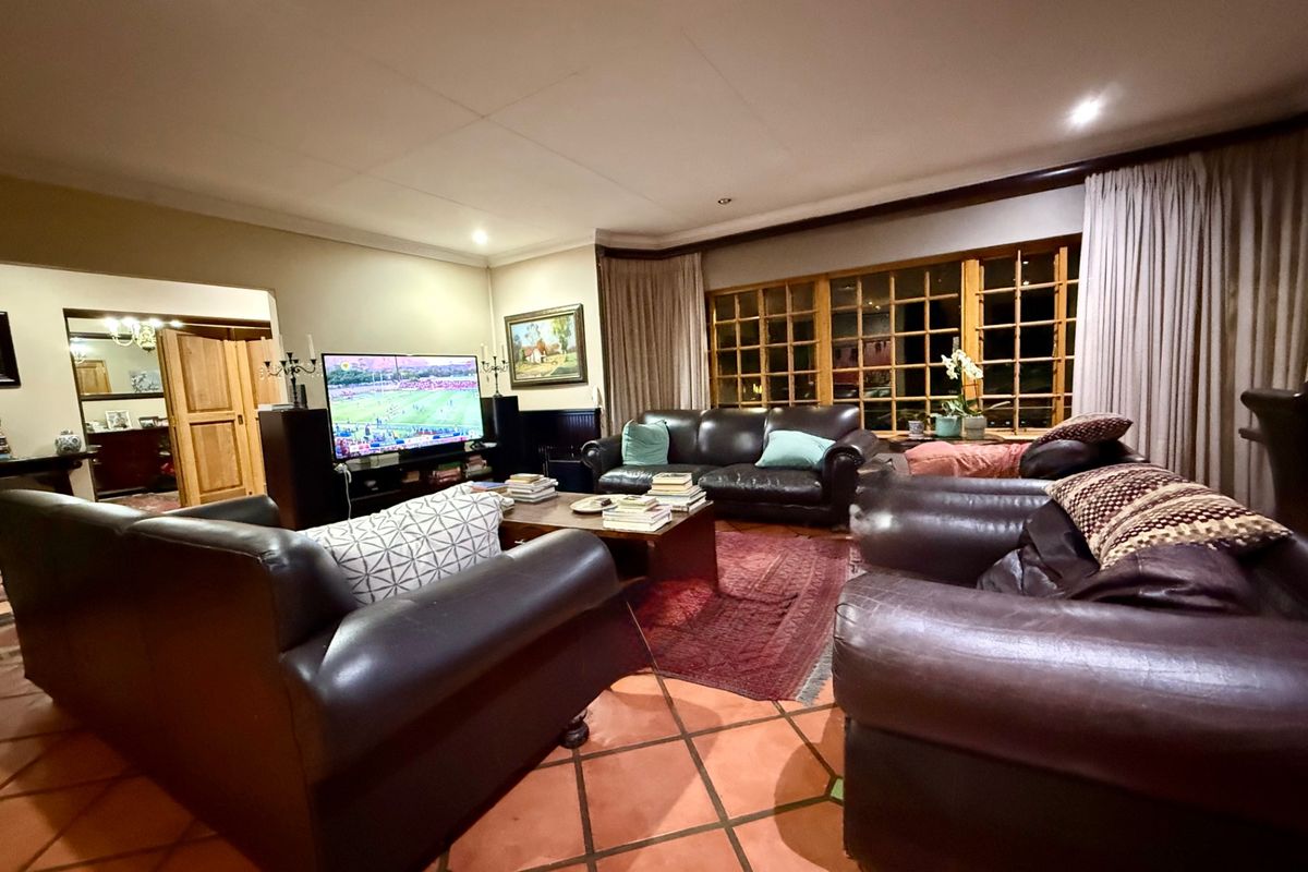 Spacious living room featuring terracotta floor tiles, large timber-framed windows, and recessed downlighting, creating a warm and inviting atmosphere.
