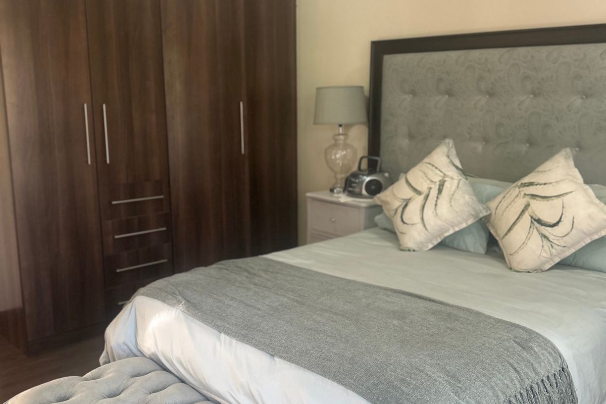 A well-maintained bedroom featuring dark wood built-in cupboards and a neutral color palette.