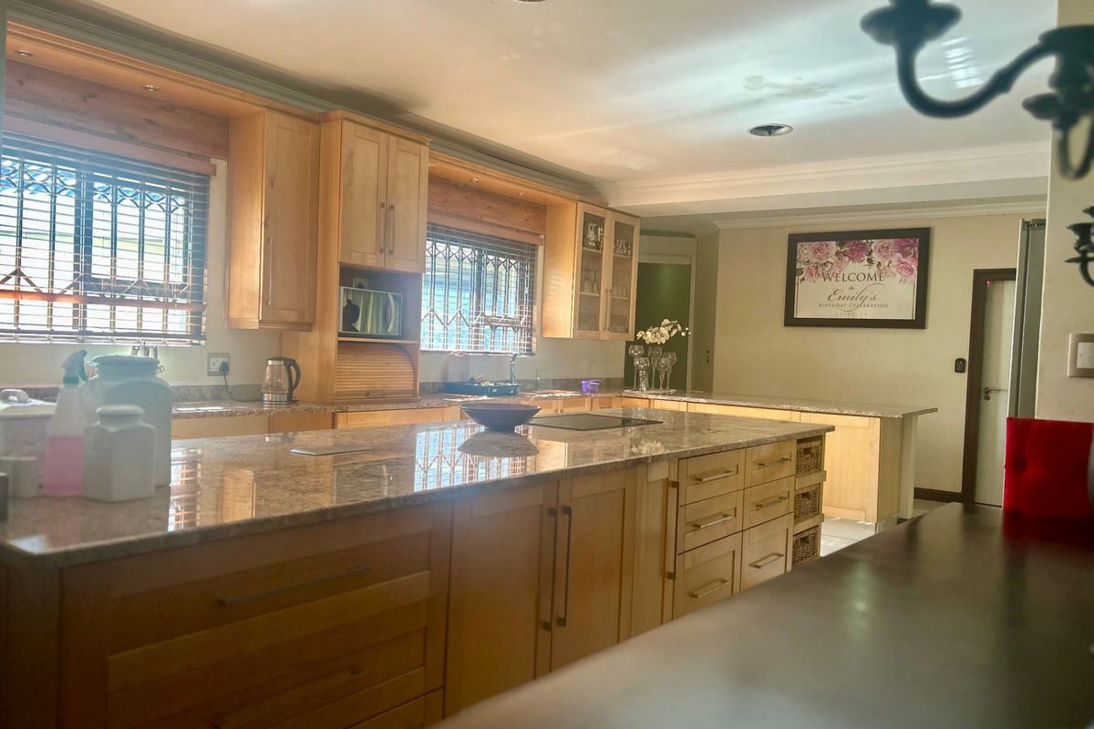 Spacious kitchen featuring light wood cabinetry, granite countertops, a large central island, and integrated storage solutions.