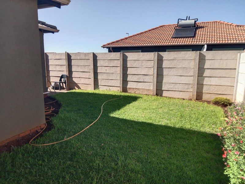 A private rear garden featuring a well-maintained lawn and a secure precast concrete boundary wall.