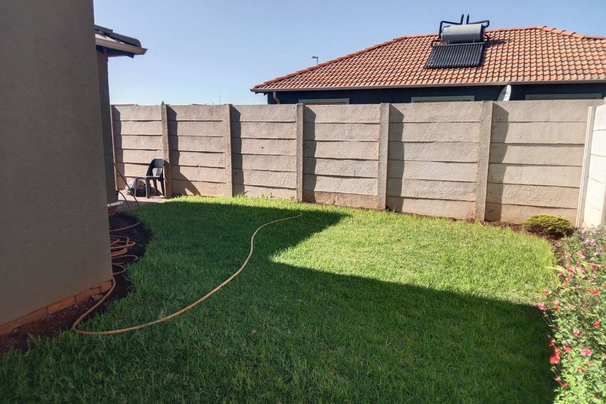 A private rear garden featuring a well-maintained lawn and a secure precast concrete boundary wall.