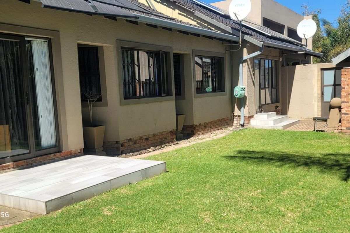 Rear exterior view of the property featuring a tiled patio, sliding glass doors, and a well-maintained lawn area.