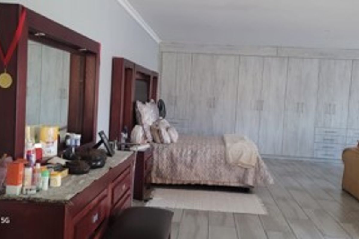 Spacious bedroom featuring extensive built-in cupboards and tiled flooring, offering ample storage and a neutral foundation for interior design updates.