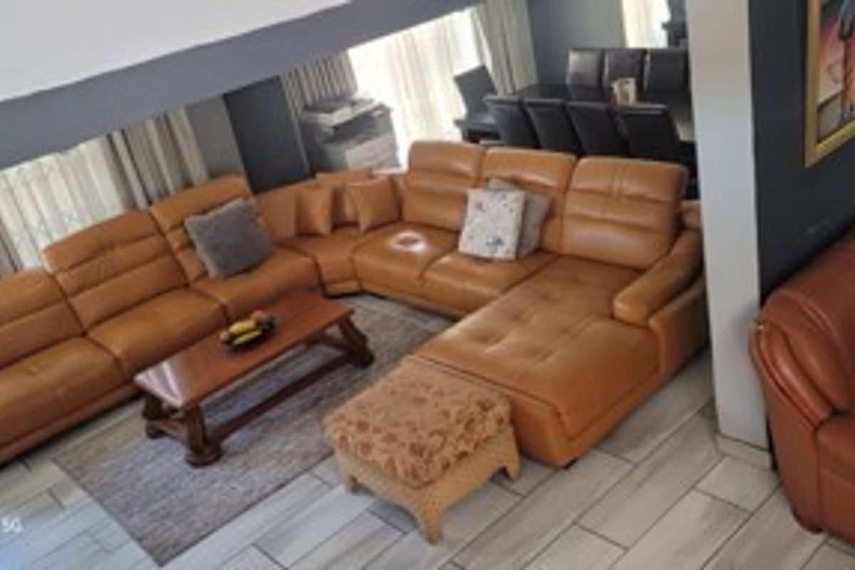Spacious open-plan living area featuring tiled flooring and a double-volume ceiling, providing a bright and airy atmosphere.