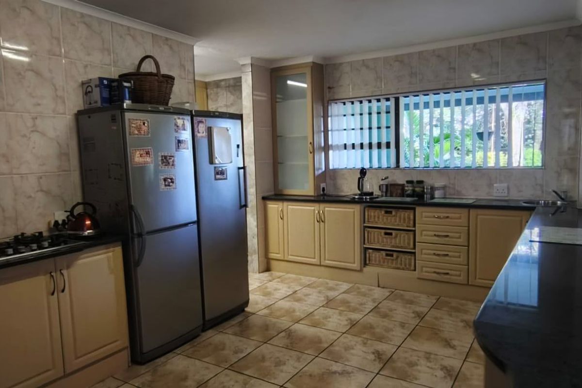 A functional kitchen featuring granite countertops, gas hob, tiled splashback, and ample built-in cabinetry with a neutral aesthetic.