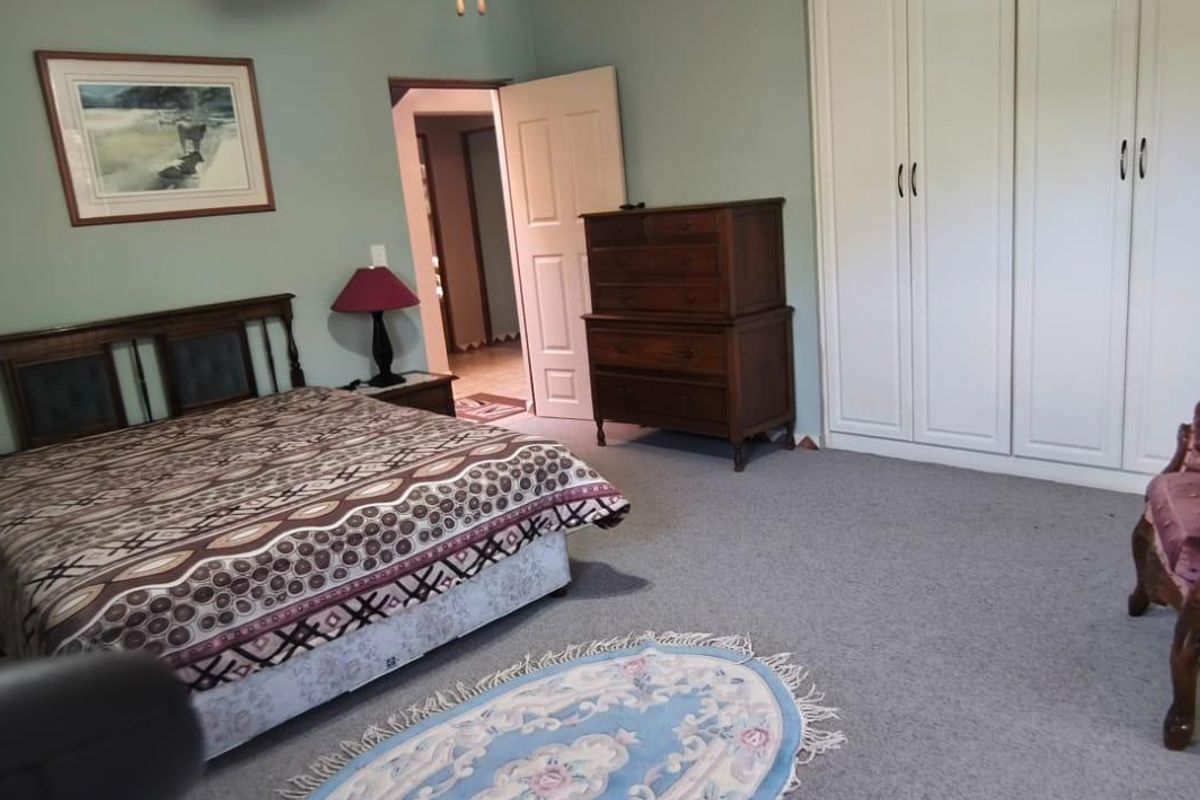 Spacious bedroom featuring neutral wall tones, carpeted flooring, and ample built-in cupboard storage.