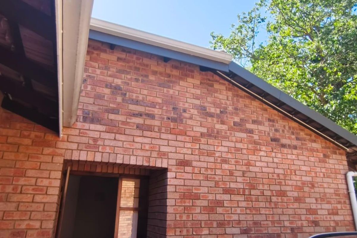 A view of the rear face brick exterior wall, featuring clean guttering, downpipes, and eaves, showcasing the property's solid construction.