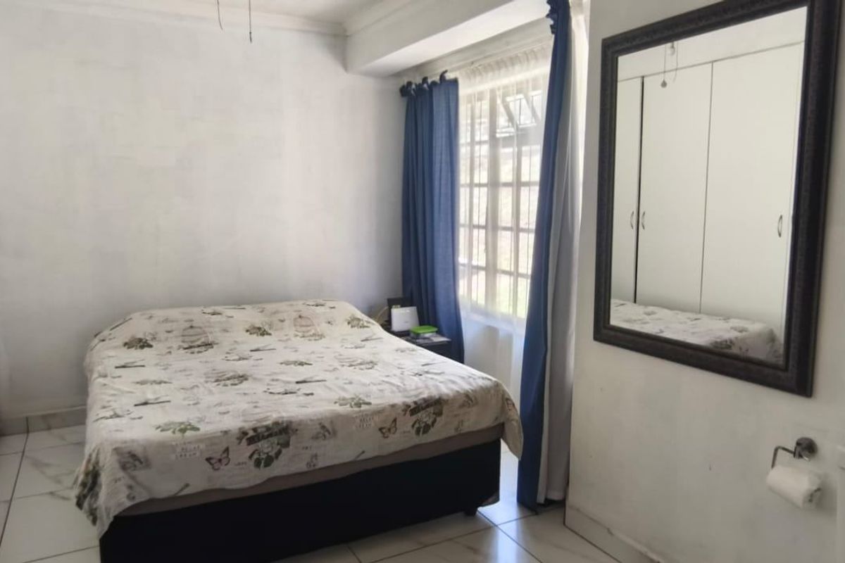 A bedroom featuring built-in cupboards and tiled flooring, with an adjacent toilet area visible in the frame.