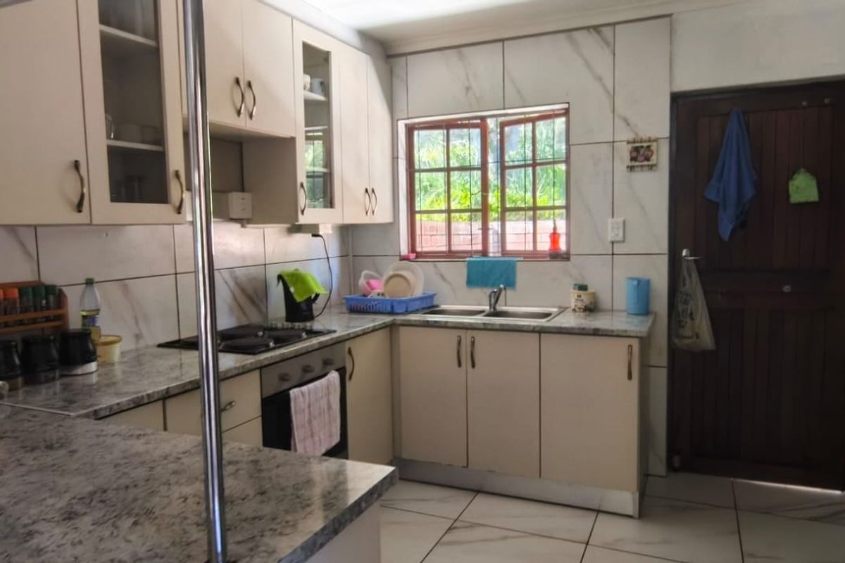 Functional kitchen featuring laminate countertops, built-in oven, electric hob, double bowl sink, and ample cabinetry with tiled backsplash and flooring.