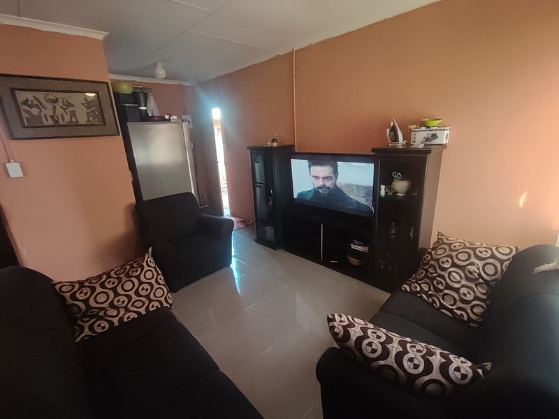 A living room area featuring tiled flooring and coved ceilings, currently used as a lounge space.