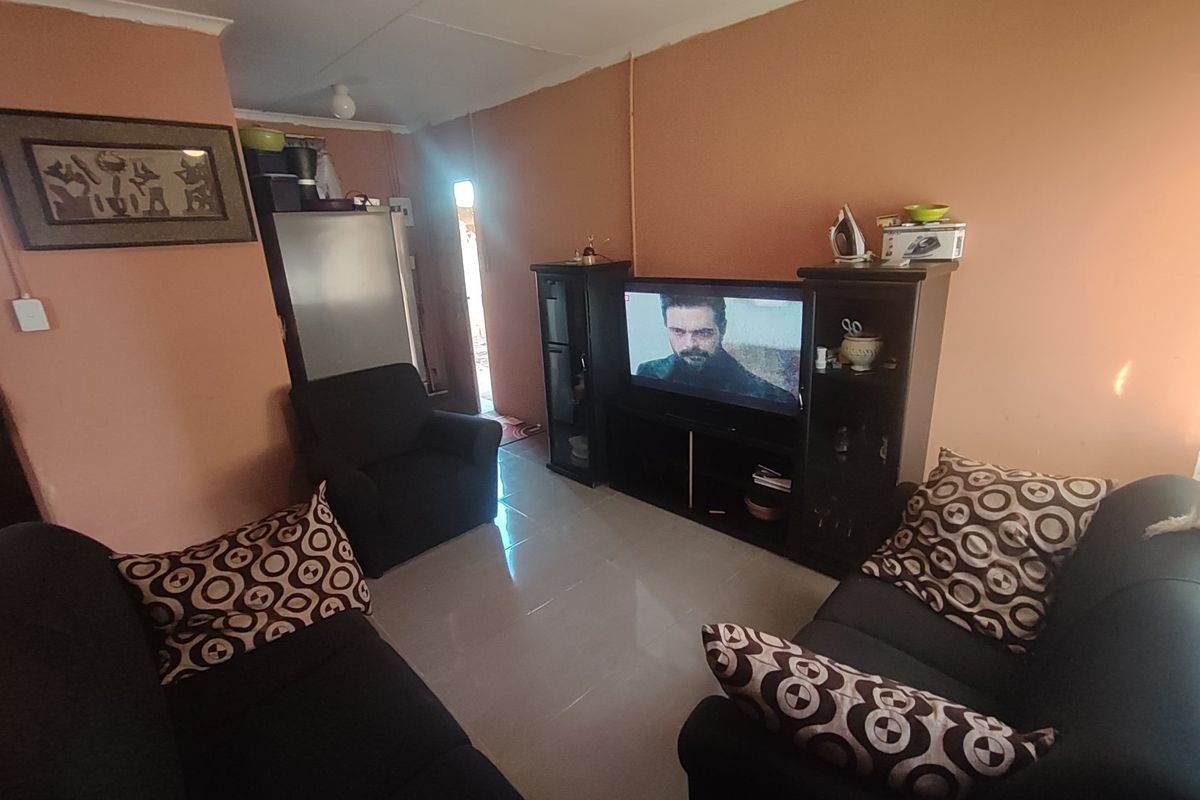 A living room area featuring tiled flooring and coved ceilings, currently used as a lounge space.