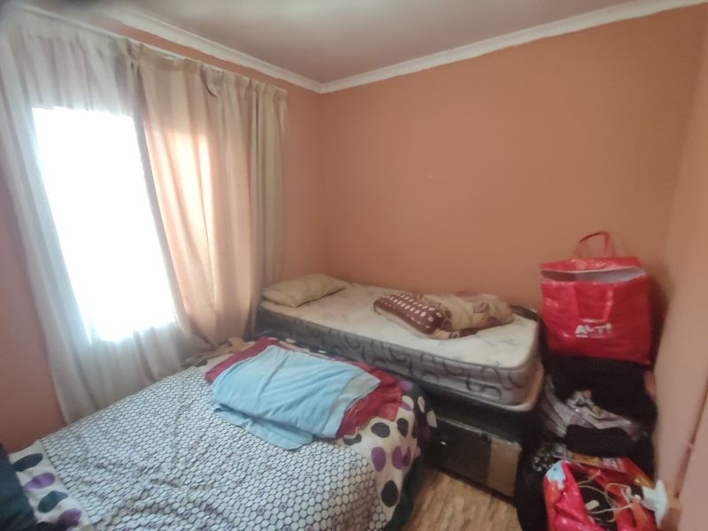 A compact bedroom featuring painted walls and a window with curtains, providing a functional sleeping space.